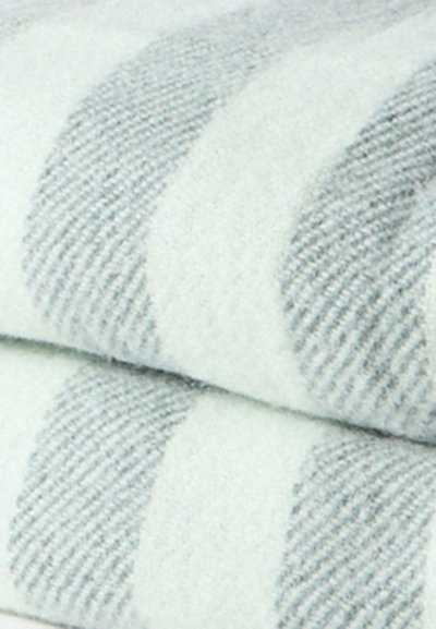 Κοντινό σε διπλωμένο ύφασμα με απαλό υφή και κυματιστό ριγωτό σχέδιο σε ανοιχτογκρι και λευκές αποχρώσεις.