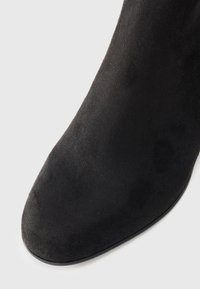 Stivale alla caviglia in suede nero con punta rotonda e una texture liscia. Il design presenta una silhouette elegante e una suola in gomma.