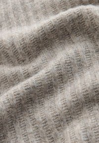 Hellbeiges geripptes Gewebe mit weicher Textur, das subtile Farbvariationen und ein gleichmäßiges Muster aus erhöhten und flachen Streifen aufweist.