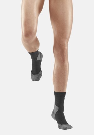 Schwarze Sportsocken mit grauen Akzenten, ausgestattet mit einem strukturierten Design und gepolsterten Bereichen zur Unterstützung des Fußgewölbes, ideal zum Laufen oder für sportliche Aktivitäten.
