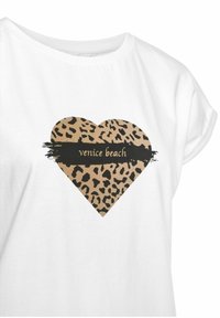 Camiseta de algodón blanca con un corazón de estampado de leopardo y una banda negra que dice "venice beach" en el centro. Mangas cortas, diseño casual.