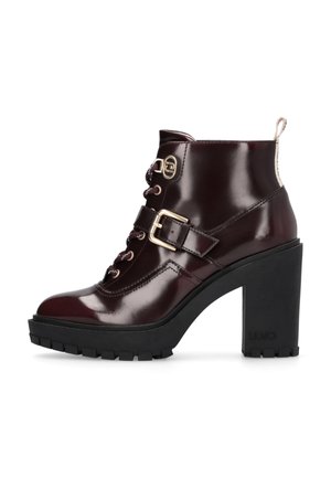 Stivaletti con tacco alto in pelle patinata bordeaux, con dettagli in pizzo e fibbia, suola piattaforma nera texturizzata e tacco in contrasto.