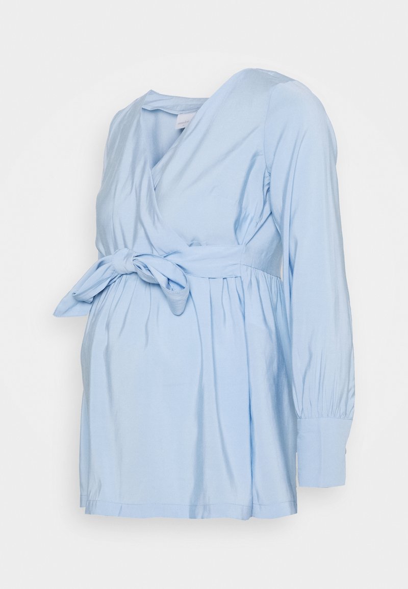 Blouse de maternité bleu clair à manches longues avec col en V, taille froncée et détail de nœud noué à l'avant.