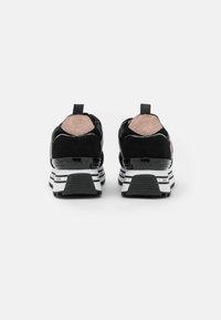 Sneakers neri con una tomaia in suede testurizzato e mesh, caratterizzati da un dettaglio rosa a contrasto, suola in gomma e intersuola bianca con strisce nere.