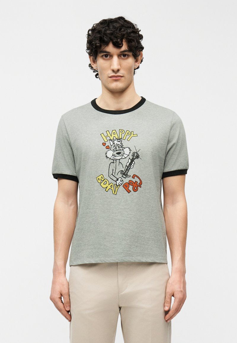 Άνδρας με σγουρά μαλλιά που φορά γκρι μπλουζάκι με μαύρη λεπτομέρεια και καρτούν γάτα που παίζει κιθάρα με το κείμενο "Happy BDAY PSG".