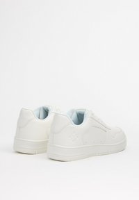 Zapatillas blancas con una superficie lisa, cuello acolchado y forro azul claro. Presentan costuras mínimas y suela de goma texturizada.