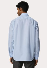 Camicia azzurra chiara con colletto standard e maniche lunghe. Tessuto liscio con polsini bottonati e orlo curvo. Design semplice.