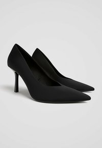 Svarta högklackade pumps med spetsig tå, slät matt finish och en smal stilettklack, med en minimalistisk design.