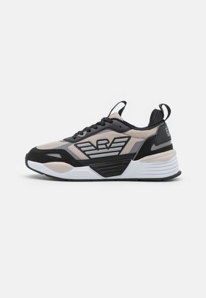 Zwarte, beige en grijze sportieve schoen met een bovenwerk van mesh, een dikke zool en een opvallend logo-opdruk aan de zijkant. Voorzien van vetersluiting en een trekkoord.