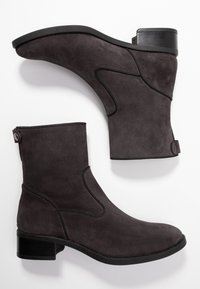 Botines de ante gris con un acabado suave, diseño minimalista, tacón bajo de bloque, panel lateral elástico y un detalle de botón en la parte trasera.