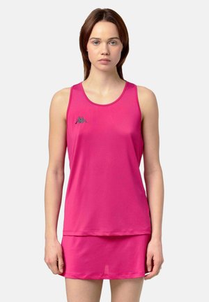 Jeune femme portant une robe de sport rose vif sans manches avec un petit logo noir de la marque sur la poitrine, debout devant un fond uni.