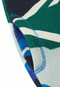 Bawełnowy sweter z mieszanką zielonych, niebieskich, granatowych i kremowych kolorów w geometryczny wzór. Widoczne niebieskie przeszycia na krawędzi.