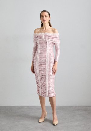 Vaaleanpunainen olkapäiltä avonainen mekko, jossa on teksturoitu kangas, röyhelökoristelu, vartalonmyötäinen siluetti ja polvipituinen helma. Yhdistettynä nude-korkokenkiin.