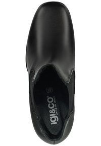 Botín de cuero negro hasta el tobillo con puntera redondeada, textura suave, paneles laterales elásticos y plantilla con marca. Hecho en Italia.