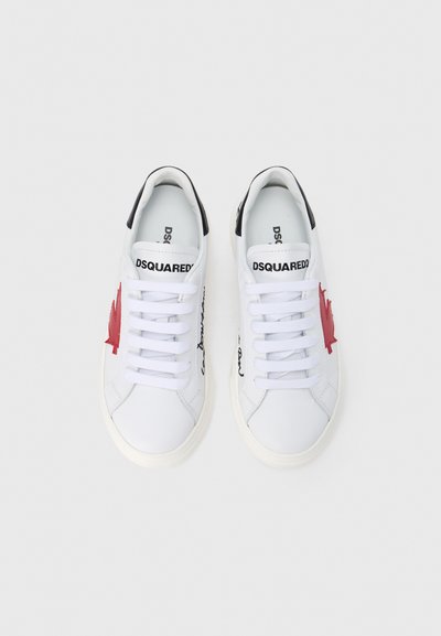 Baskets blanches avec un motif de feuille d'érable rouge et des accents noirs. Elles présentent un design à lacets et un logo brodé sur le côté.