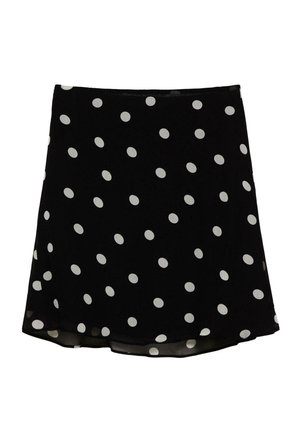 Jupe courte noire à pois blancs, ourlet légèrement évasé et texture de tissu lisse.