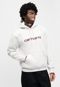 Ανοιχτό γκρι φούτερ με κουκούλα, τσέπη καγκουρό και ριμπ στα μανίκια. Διαθέτει μαρουνο κόκκινο λογότυπο "Carhartt" στο κέντρο του στήθους. Μαλακή υφή υφάσματος.