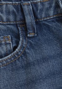 Denim tyg i mörkblått med en subtil textur. Har en midjeband med bältesöglor, kontrasterande sömmar och en framficka.