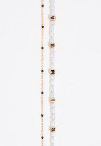 Bracelet en perles avec des perles transparentes et des perles en verre noir alternées, agrémenté d'accents en lettre dorée épelant "BAM."