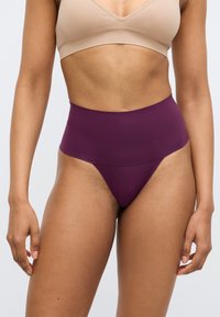 Σλιπ τύπου thong σε χρώμα δαμάσκηνο, με ψηλή μέση, κατασκευασμένο από λείο υλικό. Διαθέτει ατραυμάτιστο σχέδιο με φαρδύ λάστιχο στη μέση για άνεση.