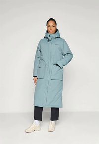 Svetlomodrý, dlhý nepremokavý kabát s kapucňou, predným zipsom a dvoma veľkými vreckami. Má hladkú tkaninu a moderný dizajn.