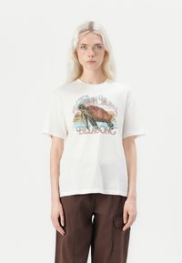 Hvit T-skjorte med et fargerikt grafisk motiv av en skilpadde og teksten "Besøk de hawaiianske øyer Billabong." Korte ermer og avslappet passform.