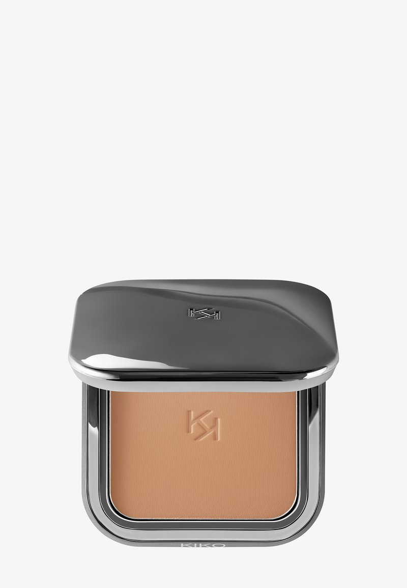 Kompakt makeup-puder med präglad logotyp, förpackat i ett stilrent metalliskt silverfodral med delvis stängd lock.