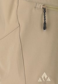 Tissu beige avec coutures surpiquées, une tirette de fermeture éclair avec cordon noir et blanc, et un petit logo brodé composé de trois formes géométriques.