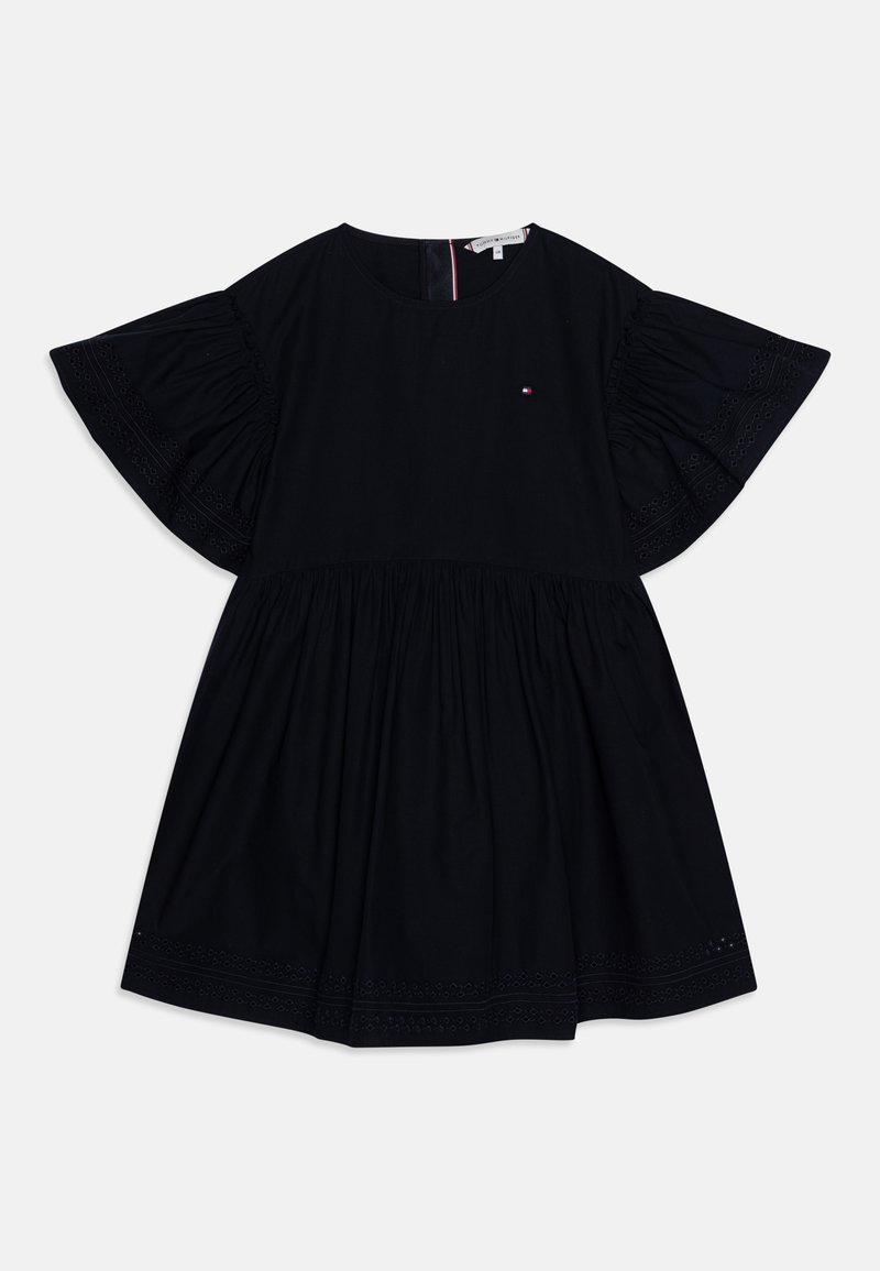 Juoda trumpa suknelė su plataus siuvinėtų rankovių ir apykaklės, susirinkusių juosmeniu, apvalia iškirpte ir mažu raudonu, baltu ir mėlynu logotipu krūtinėje.