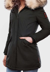 Dunkelgrüne Parka-Jacke mit Kapuze aus Kunstpelz, Reißverschluss, Seitentaschen und strukturiertem Stoff. Mit einem Logo-Patch am Arm.