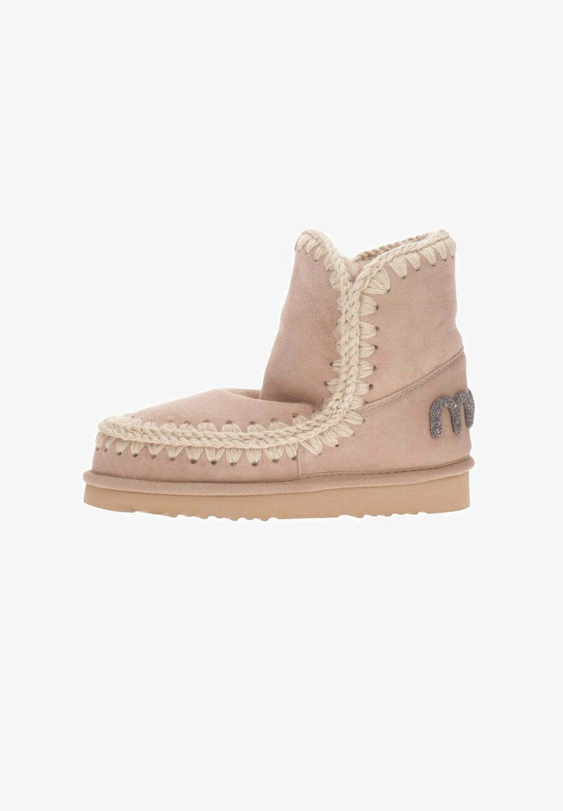 Lys pink suede ankelstøvle med en tekstureret cremefarvet syning omkring toppen og en glitrende logoaccent på siden. Flad sål.