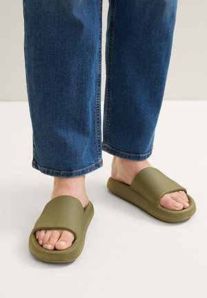 Sandales à glissière vert olive avec un dessus texturé, une large sangle et une semelle épaisse, associées à un jean en denim bleu légèrement ample.