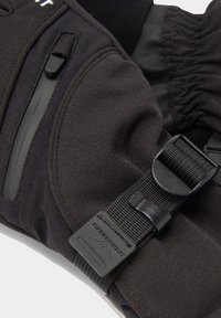 Scaldino in tessuto nero con cinturino regolabile, dotato di superficie liscia, più tasche di stoccaggio e una patch con logo.