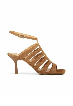 Sandale à talon haut en daim marron clair avec des brides découpées et une bride à boucle à la cheville, avec un talon fin et effilé sur fond blanc.