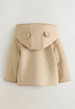 Beige huppari, jossa on tilkkupistoin tehty takaosa, iso huppu ja pyöristetyt korvat. Pehmeä pinta, rento muotoilu ja suora helma.
