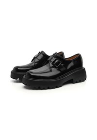 Zapatos de charol negro con suela de goma gruesa, que presentan una hebilla decorativa y una textura suave. Punta redondeada y diseño elegante.