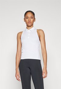 Top polo bianco senza maniche con colletto e chiusura a bottoni, realizzato in tessuto morbido, abbinato a leggings neri aderenti.