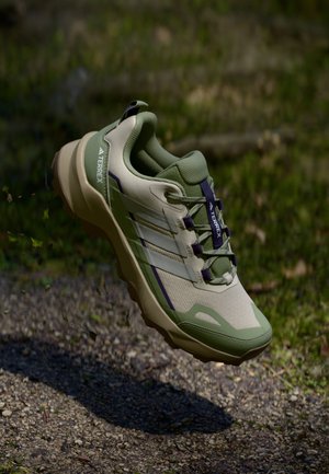 Chaussure de randonnée légère en vert et beige, dotée d'un dessus texturé, d'un col rembourré et d'une semelle en caoutchouc durable avec un motif de crampons profond.