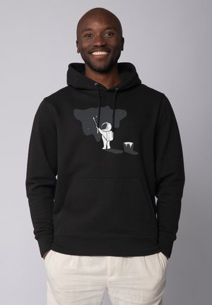Black hooded sweatshirt featuring an astronaut graphic in white, with a starry background and a paint bucket. Soft fabric, relaxed fit.