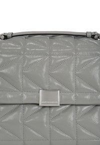 Borsa grigia trapuntata realizzata in materiale lucido, con una chiusura metallica in argento con branding impresso e motivi di cucitura angolari in tutto il suo design.