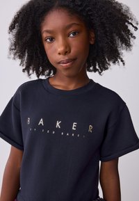 Marineblaues T-Shirt aus Baumwolle mit einem goldfarbenen Aufdruck des Logos "BAKER by TED BAKER" auf der Brust, mit kurzen Ärmeln und rundem Halsausschnitt.