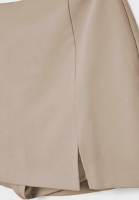 Bež podrobnost tkanine krila, ki prikazuje bočni razrez s čistim šivanjem in gladko teksturo.