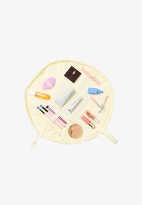 Trousse de maquillage circulaire jaune contenant pinceaux, poudre, recourbe-cils, sérum, fond de teint, gloss à lèvres et éponge de beauté disposés à l'intérieur.