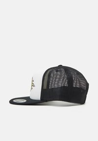 Gorra de camionero con la parte frontal blanca y la malla trasera negra, presenta un visor plano negro y un diseño gráfico amarillo en el panel frontal.