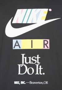 Logo de Nike avec des rayures multicolores, un swoosh blanc, AIR en blocs colorés, et le slogan "Just Do It." sur fond noir.