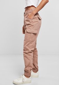 Cargo kalhoty v jemné růžové látce, s tapered nohavicemi, elastickými manžetami, dvěma bočními kapsami a dvěma cargo kapsami na stehnech.