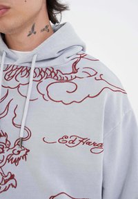 Felpa grigia con cappuccio caratterizzata da un intricato ricamo di un drago rosso e nuvole, con il nome del marchio "Ed Hardy" in corsivo, in cotone, vestibilità standard.