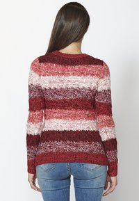 Sweter robiony na drutach w poziome paski w kolorze czerwonym, białym i bordowym; teksturowany wzór; okrągły dekolt; długie rękawy; luźny krój.