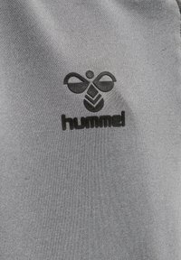 Grauer Baumwollstoff mit einem erhabenen schwarzen Logo einer Biene und dem Markennamen "hummel" darunter, mit einer glatten Textur.