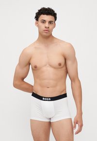 Fehér boxer alsónadrág, puha anyagból, fekete elasztikus derékbanda 'BOSS' logóval. Klasszikus szabás, varrás nélküli dizájn.